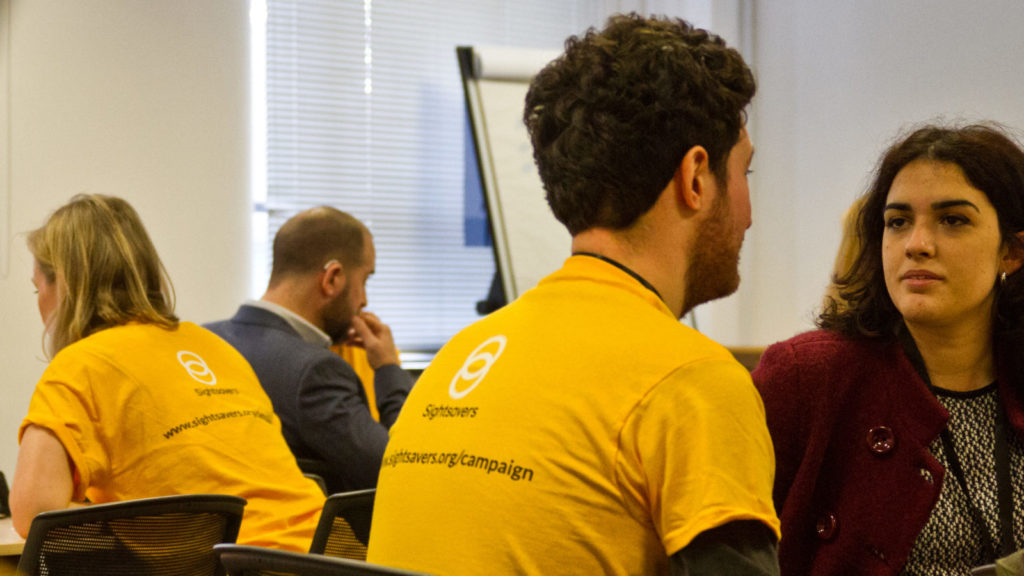 A photo of Sightsavers employees wearing the branded yellow tshirts at an event.