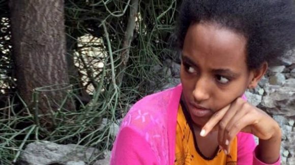 Rahel sits quietly outside her home.