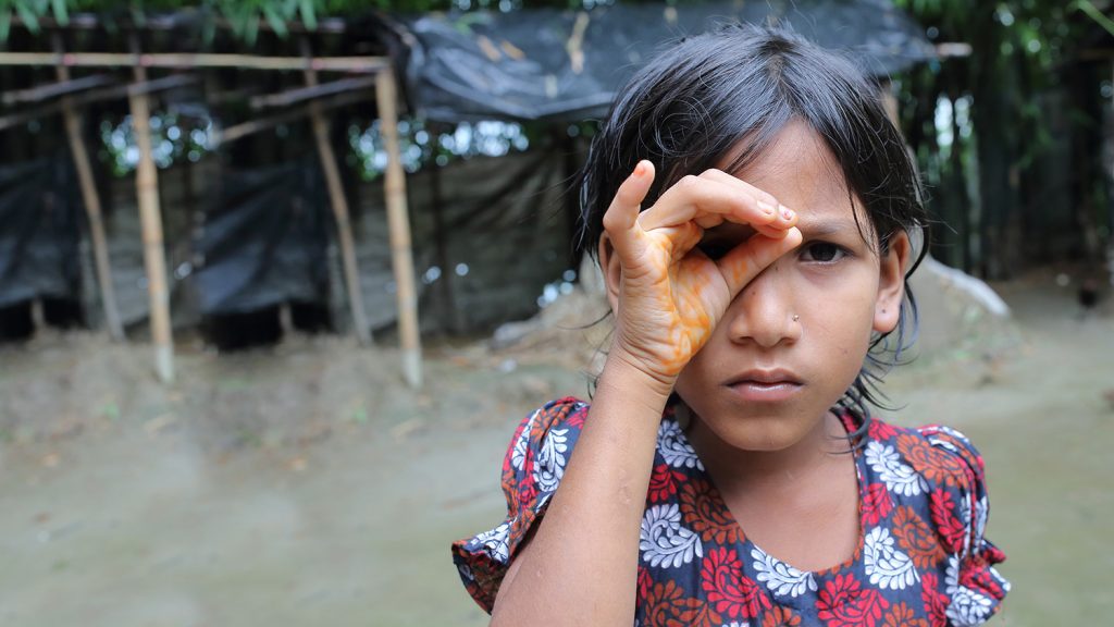 En ung flicka kupar handen för ena ögat i ett försök att skärpa synen.