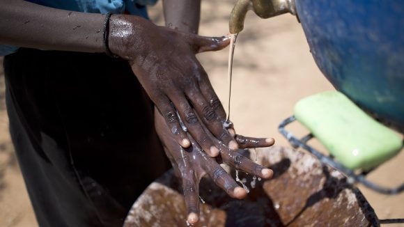 En närbild av ett barn som tvättar händerna under en kran.
