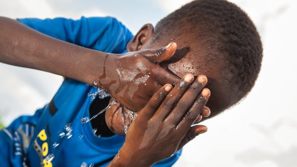En pojke tvättar ansiktet för att förebygga spridning av trakom.