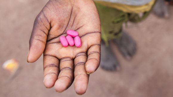 Ett barn i Senegal håller fyra Zithromaxtabletter i handen.