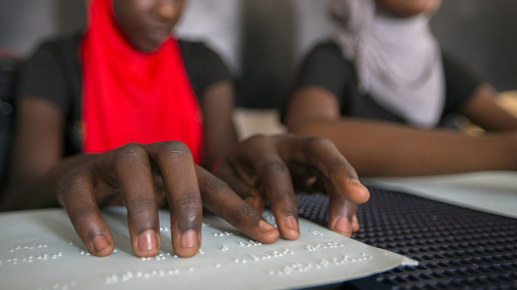 En skolelev i Senegal läser blindskrift i klassrummet.