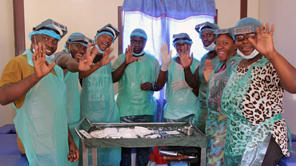 En grupp trakomkirurger i Zambia ler mot kameran, de bär operationskläder.