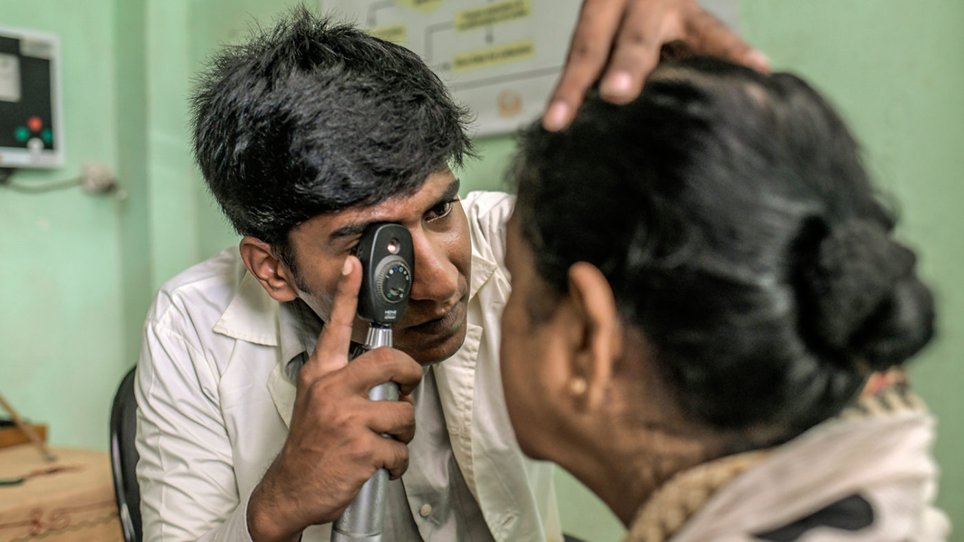 En sjukvårdare undersöker ögonen på en kvinna.