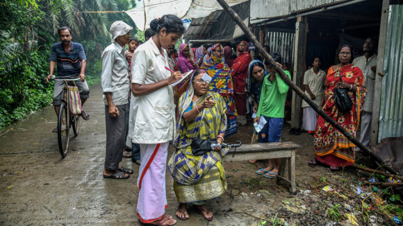 En kvinna får sina ögon undersökta av sjukvårdspersonal utomhus under en undersökning i Indien.