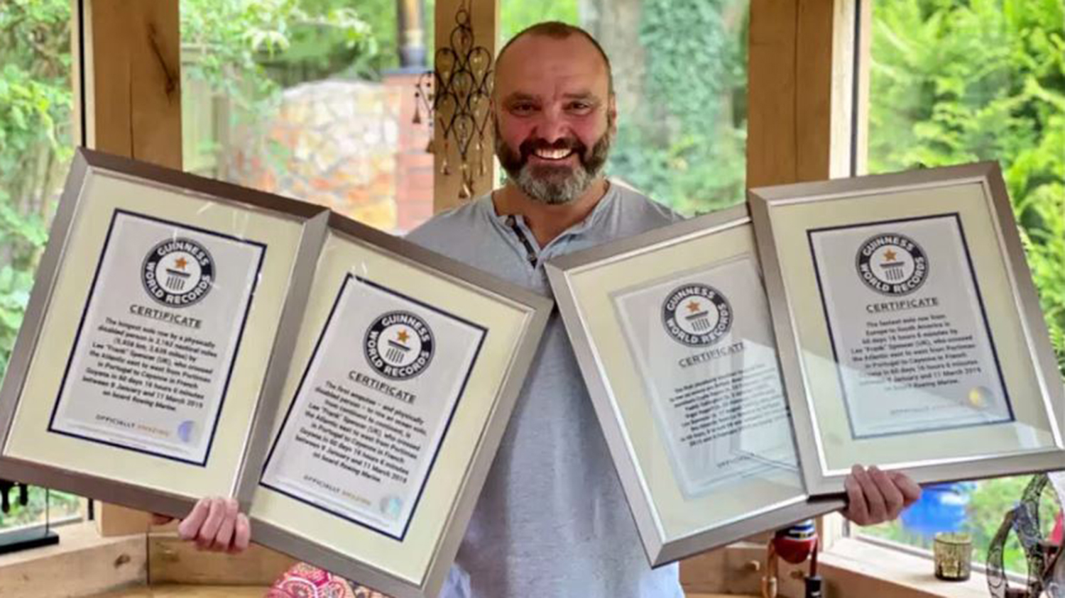 Lee Spencer håller upp sina certifikat från Guinness rekordbok.
