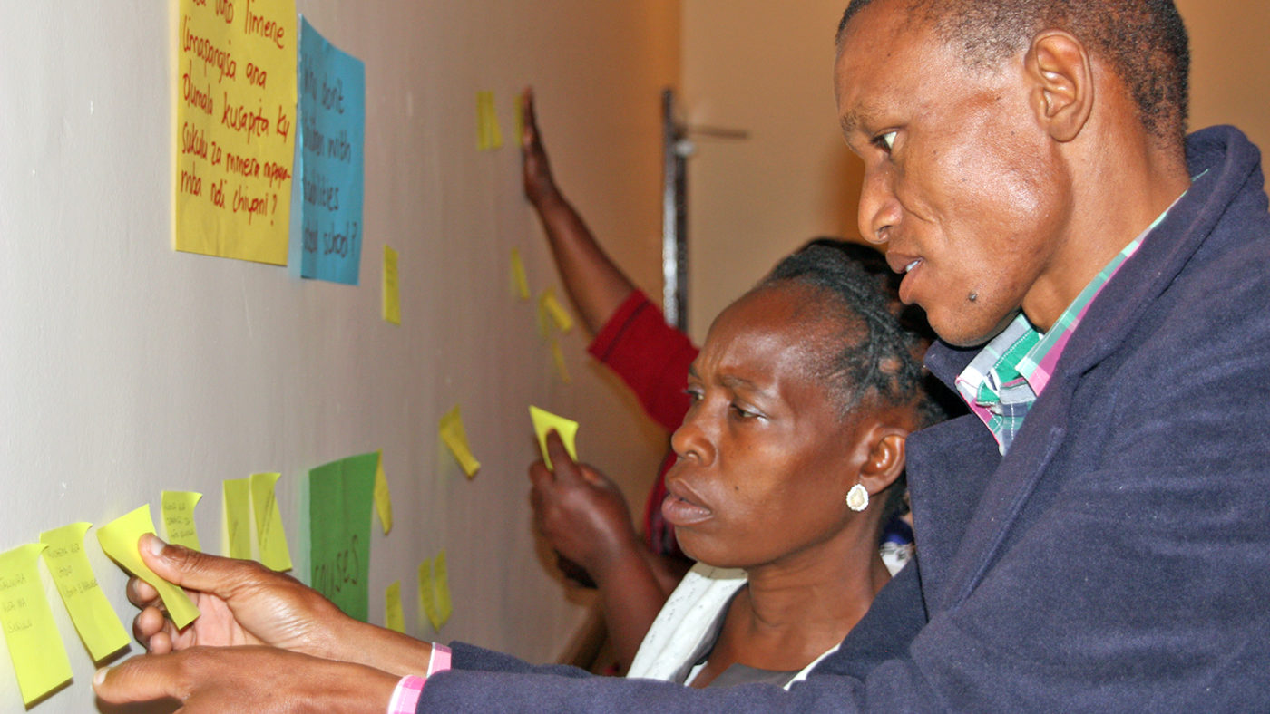 Two people reading notes on a wall during a workshop.