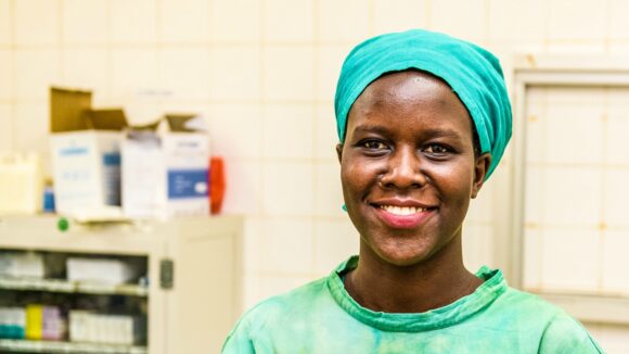 Gladys Atoo ler mot kameran, hon är klädd i sin läkaruniform.