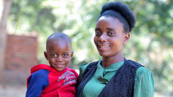 Catherine håller om sin lille son Wonderful medan de båda ler mot kameran i Malawi.
