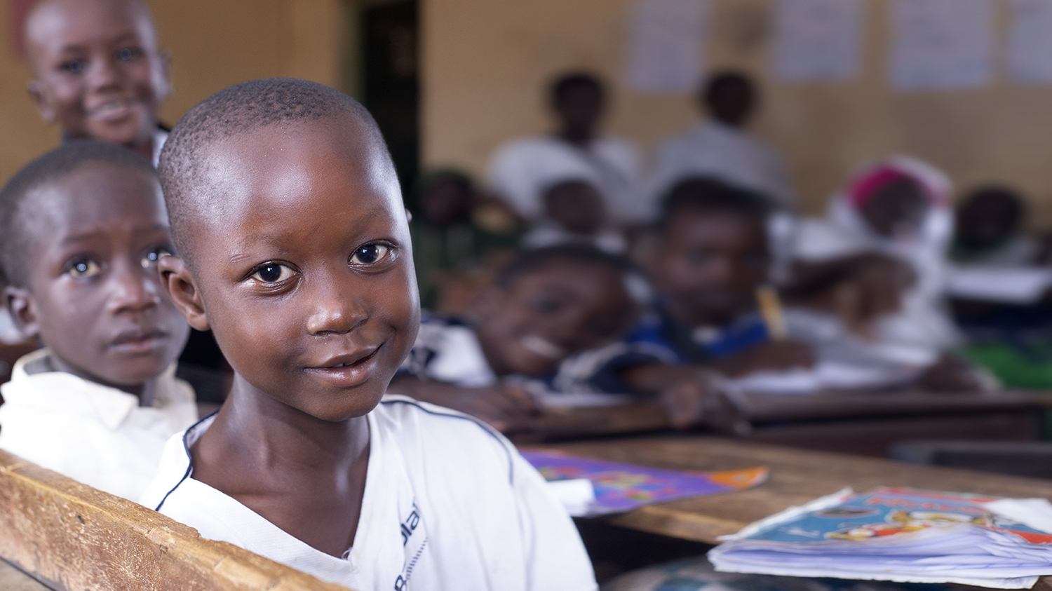 En ung student i Nigeria ler i klassrummet.