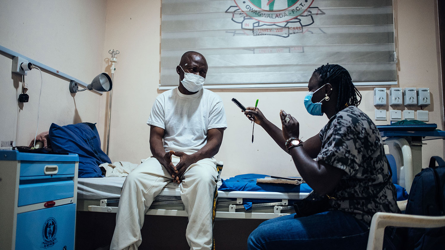 En man med glaukom sitter på en sjukhussäng och intervjuas av en Sightsavers-anställd.