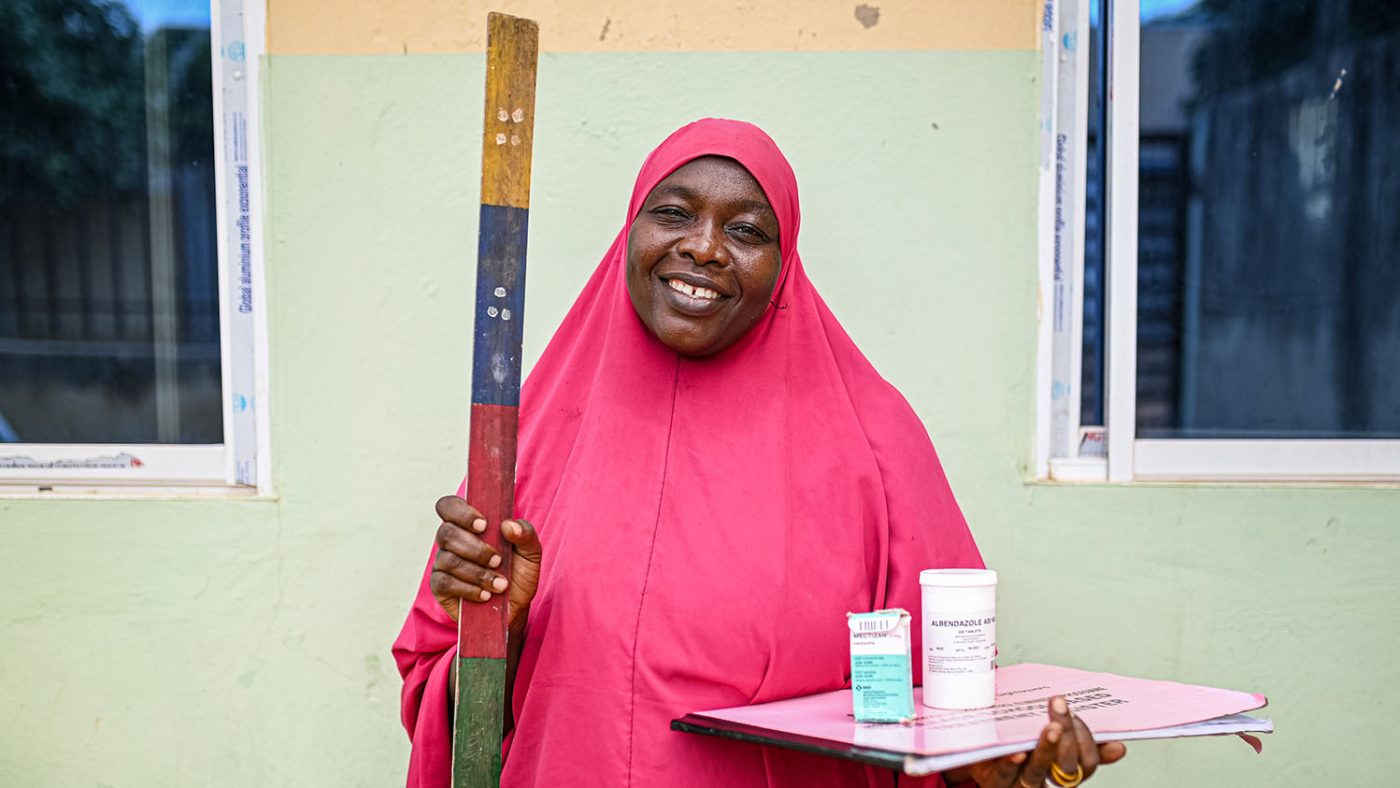 Läkemedelsdistributören Amina håller i en dosstång, pappersarbete och medicin.